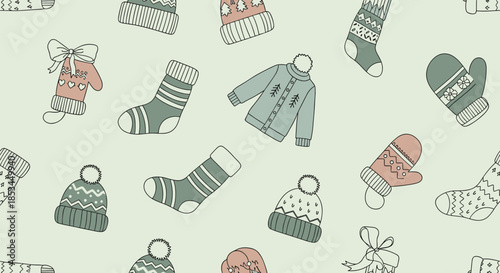 Seamless pattern with cozy hand-drawn winter clothing items like hats, mittens, socks, and sweaters on a light green background.