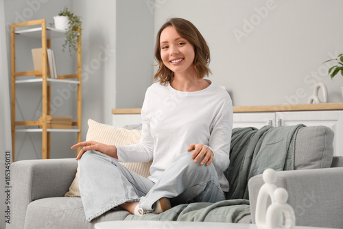 Free Download Beautiful young woman with short curly hair sitting on sofa at home - GFXLoad