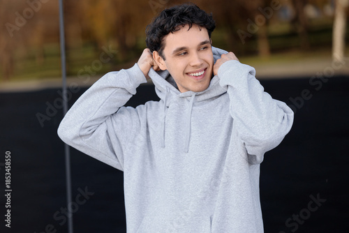 Young man in grey hoodie ou...