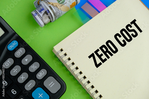 calculator and white note pad with text ZERO COST as a financial and business concept on grey background.
