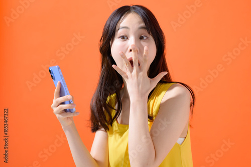 スマホを持って驚く女性