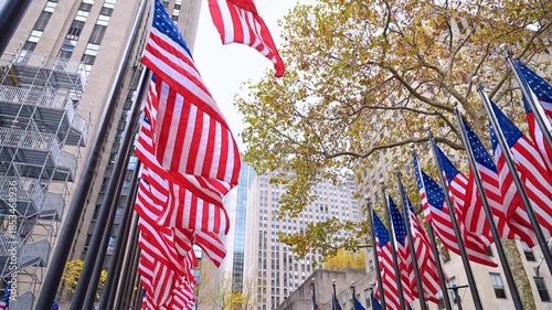 American flags across Rockefeller buildings. American flags stretch above the plaza surrounded by tall Rockefeller Center buildings.