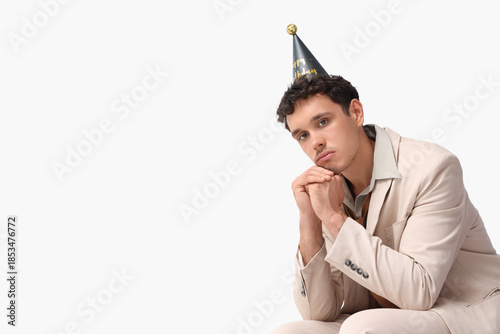 Sad young man in party hat ...