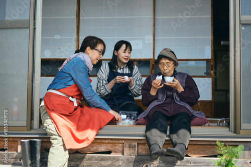 日本の縁側でおやつを食べながら休憩する
三世代の女性達