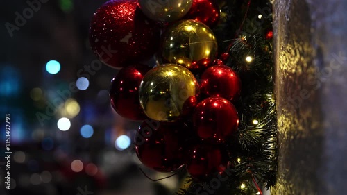 Shiny round Christmas tree ornaments displayed as part of a luxury boutique entrance decoration on a city street, creating an elegant and festive holiday atmosphere.