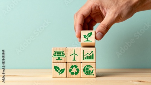 Hand placing wooden blocks with eco symbols