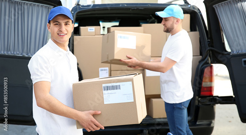 Delivery men taking parcels from car outdoors