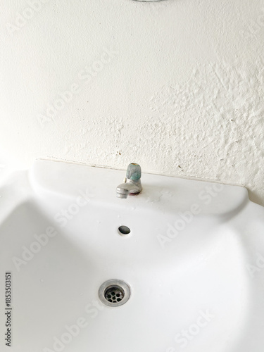 Broken Washbasin on Damped, Musty Old Painted Wall with Light. Textured Exterior Toilet Wall in Room at Dhamma Retreat Center, Saraburi, Thailand. 25 OCT 2025. A.M.