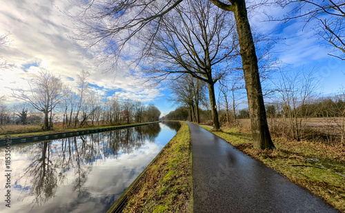 Schilderij op canvas A beautiful and scenic canalside path surrounded by tranquil skies and stunning