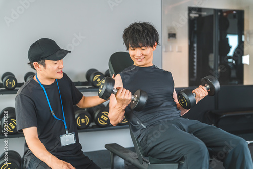 Bild auf Leinwand Men and male trainer doing dumbbell training at a fitness gym