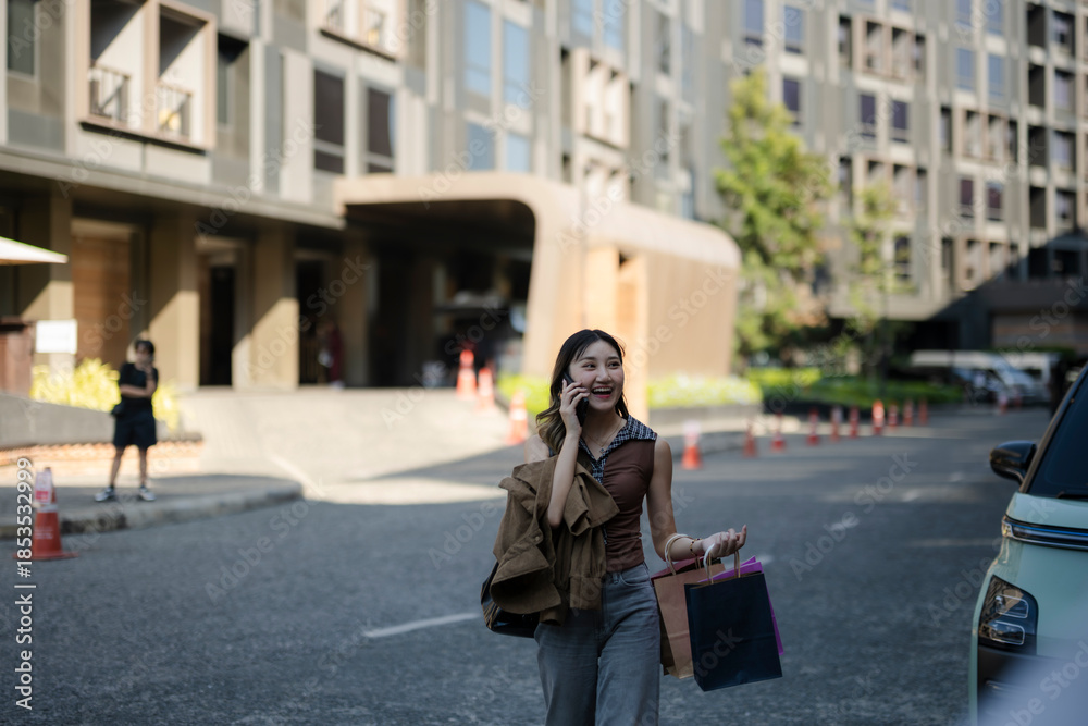 Fototapeta premium Woman walking, carrying shopping bags and talking on phone