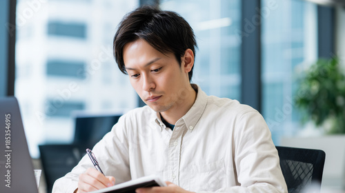 Businessman writing in notebook at desk