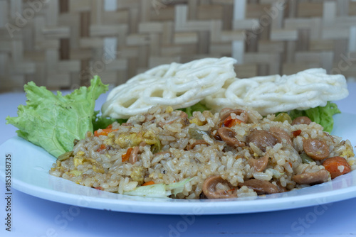 Nasi goreng or Delicious Indonesian fried rice with sausages and crispy crackers on a plate