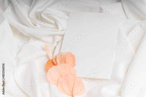 Minimalist card on white fabric with dried flowers.