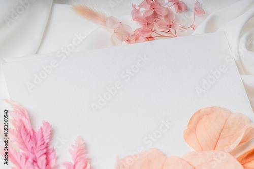 Minimalist card on soft white fabric with pink dried flowers.