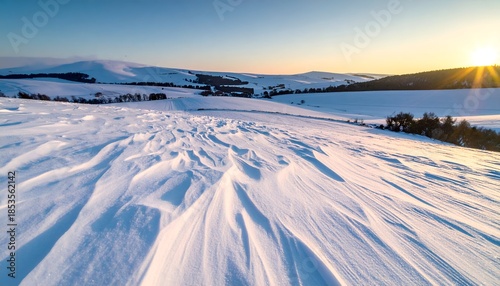Wide-angle view of a snow-covered landscape with rolling hills bathed in warm sunlight