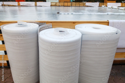 Photos Three rolls of white polyethylene insulation film stand upright and are ready for use
