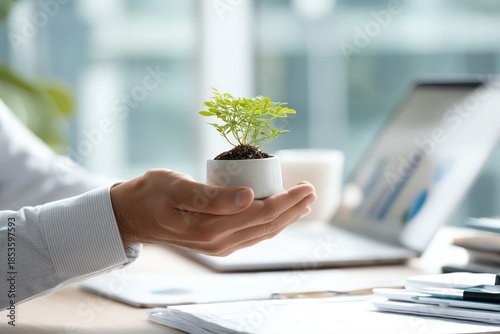A hand holding a small plant in a pot, symbolizing growth and environmental awareness.