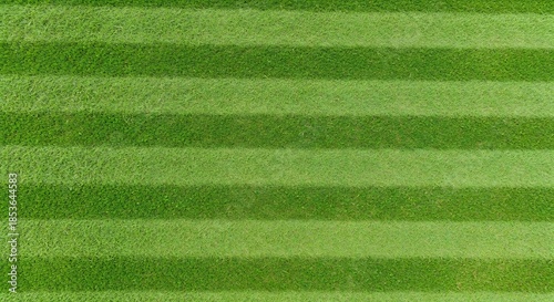 Perfectly striped green grass field, lush, viintimate apparelnt, and meticulously manicured, ideal for sports and recreation.