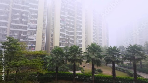 ground panning shot showing multi storey skyscraper builds hidden in the fog smog pollution in the winter in delhi gurgaon noida gaziabad showing the visibility and air quality challenges