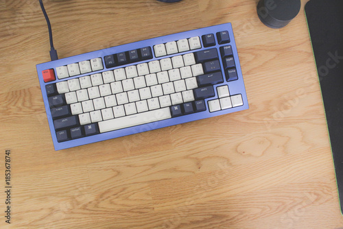 High angle view of mechanical keyboard on wooden desk, minimalist workspace setup.