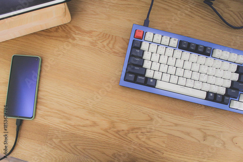 High angle view of mechanical keyboard on wooden desk, minimalist workspace setup.