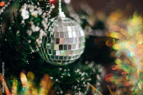 A shiny Christmas tree decoration hanging from dark green branches creates a festive atmosphere.