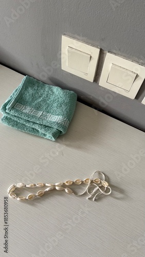 Seashell Necklace and Folded Towel on White Surface