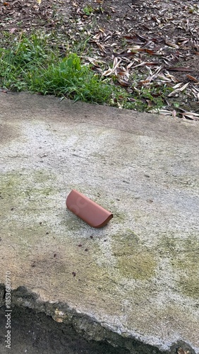 Brown Sunglasses Case on Rough Concrete Pavement