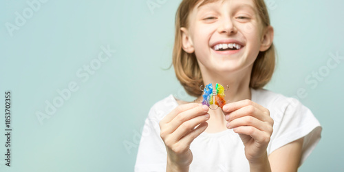 Tableau sur toile Smiling child holds rainbow orthodontic retainer on pastel background with copy space for dental clinic banner and kids care promotion