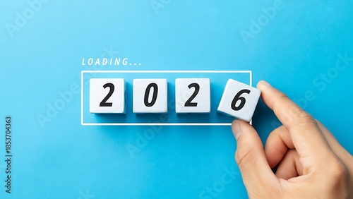 Hand placing the final piece to complete the year 2026 with white blocks