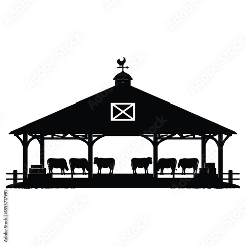 Silhouette of cows inside open barn structure