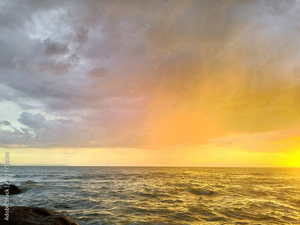 Obraz premium Catching scenic dawn with sunset sky at Bali, Indonesia, with nice waves and low tides, along with summer breeze for a perfect holiday, romantic, and traveling experience.