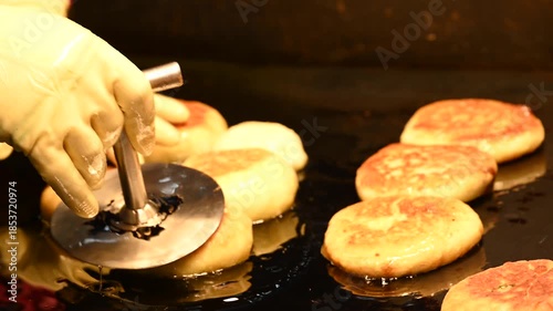 A vendor fries hotteok, a Korean sweet pancake, in hot oil at a market in Myeongdong, South Korea.