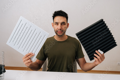 Tableau sur toile Portrait of man comparing soundproof acoustic panels for sound absorption and insulation, demonstrating options for home studio and interior sound treatment solutions, reviewing different materials