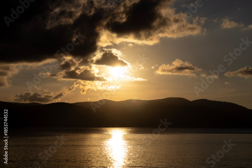 Dramatic Golden Sunset Over Ocean and Mountain Silhouettes
