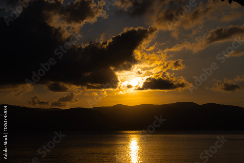 Dramatic Golden Sunset Over Ocean and Mountain Silhouettes
