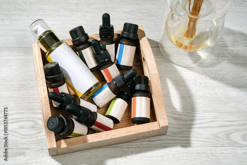 photograph of many essential oil bottle with colored label put in the wooden block on wooden table