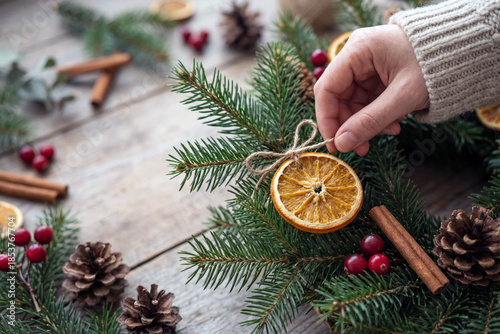 Christmas wreath evergreen branch dried orange hand cinnamon stick pine cone red berry rustic table natural decoration winter holiday
