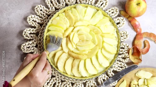 Woman preparing Apple Tart Pie Centered on Rustic Plaited Doily with Fresh Apple Slices and Cutlery