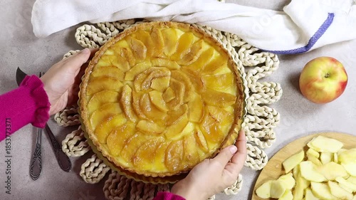 Woman preparing Apple Tart Pie Centered on Rustic Plaited Doily with Fresh Apple Slices and Cutlery
