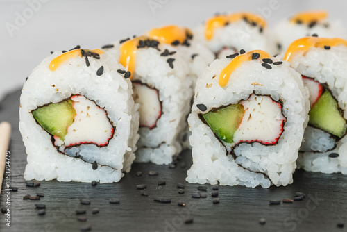 California sushi rolls filled with imitation crab, cucumber, and topped with sesame seeds and sauce.