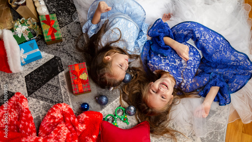 Top view cute children play lying on the floor in a festively decorated room, against the background of a Christmas tree