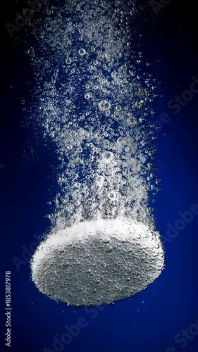 Effervescent tablet dissolving underwater, releasing streams of bubbles against a deep blue background. The video is generated from my real photo.