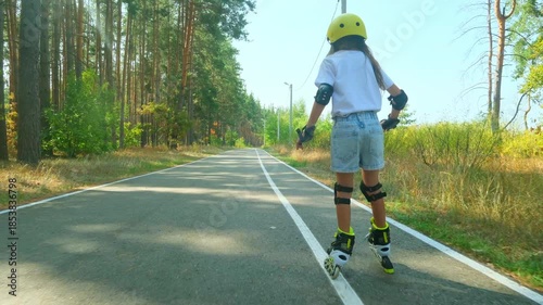 Girl is roller skating by forest, enjoying an active hobby in the open air.