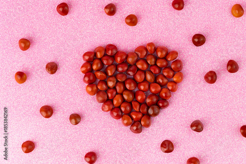 Heart Shape of Red Saga Seeds (Adenanthera pavonina) on Pink Glitter