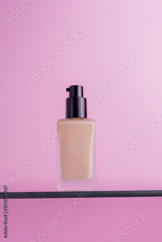 Elegant glass bottle of liquid foundation with black pump dispenser on a shelf