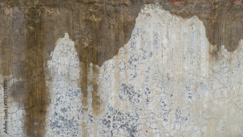 A weathered concrete wall with peeling paint and rough texture viewed from a ...