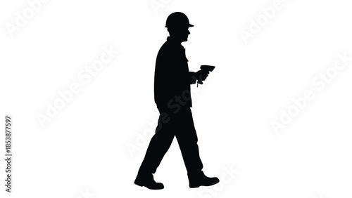 Silhouette of a construction worker in a hard hat walking while holding a handheld scanner device