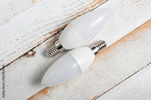 Two LED lamps with E14 sockets lying on a wooden surface.